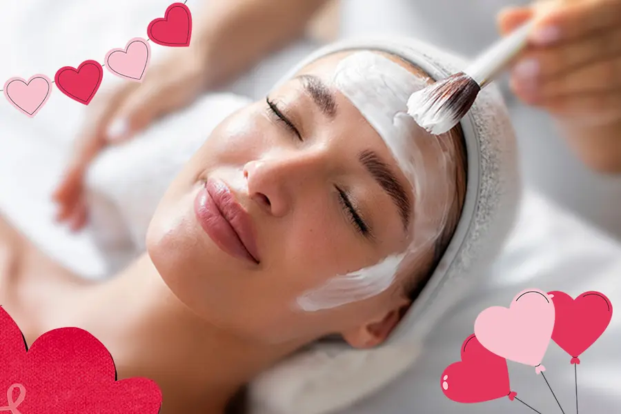 glowing-results-special-valentines-day A relaxed woman with hearts around her head as she's getting facial cream spread on her face