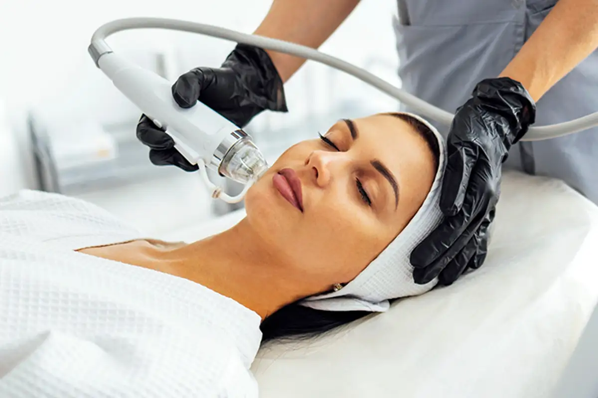 Woman getting Deep Cleanse & Exfoliation cream brushed on her face and forehead. 