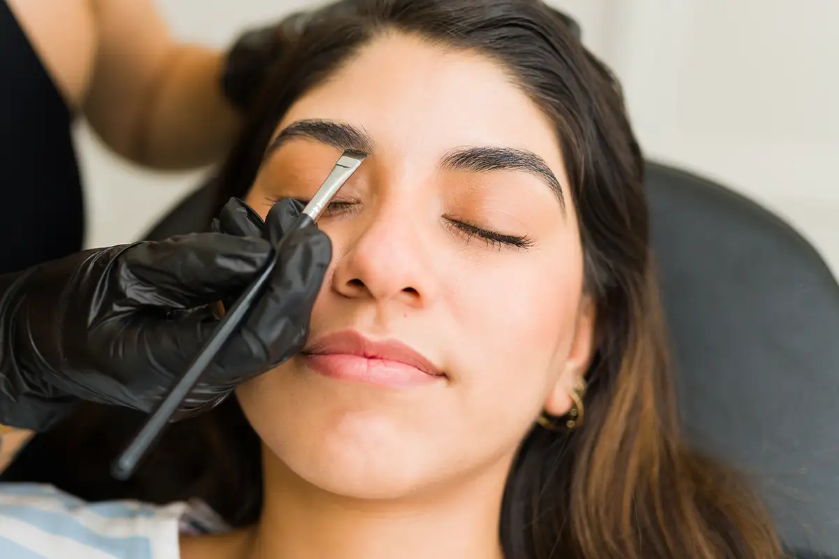 A relaxed woman getting facial cream spread on her face