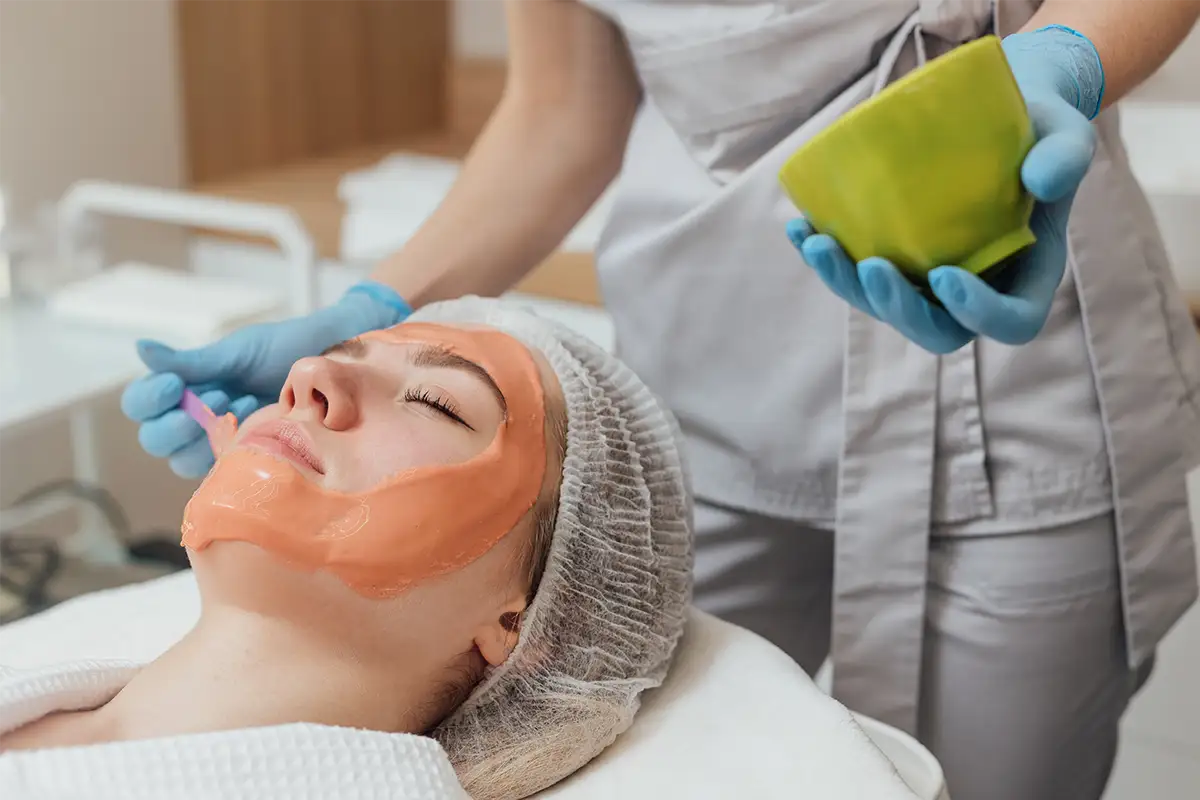 A relaxed woman getting facial cream spread on her face