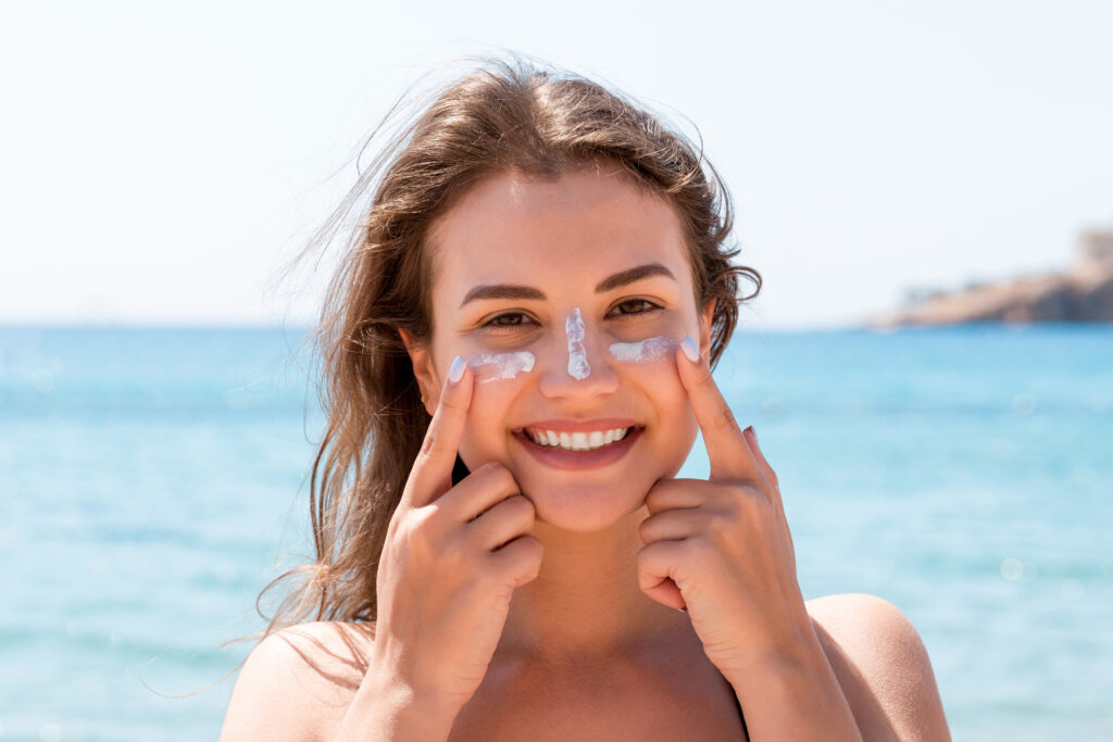 Woman applying sunscreen on her face before stepping outside in the bright Florida sun.