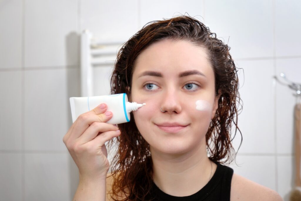 Young woman applying facial sunscreen to stay protected in sunny Florida weather.