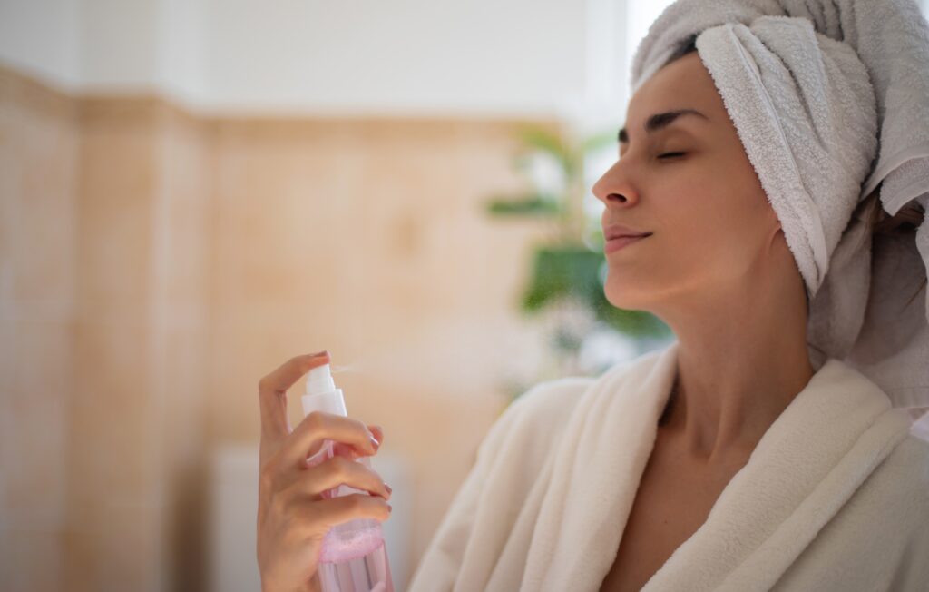 A woman applying rose water for skin hydration to calm irritation and refresh her complexion.