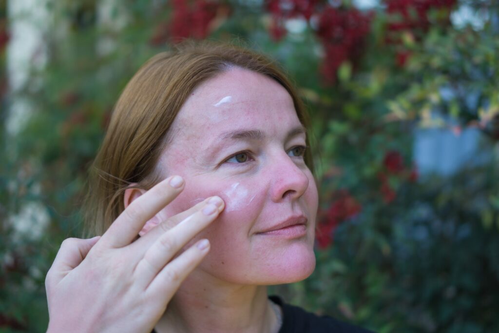 Woman gently applying soothing skincare to sun-exposed skin after a day outdoors in Florida sunshine.