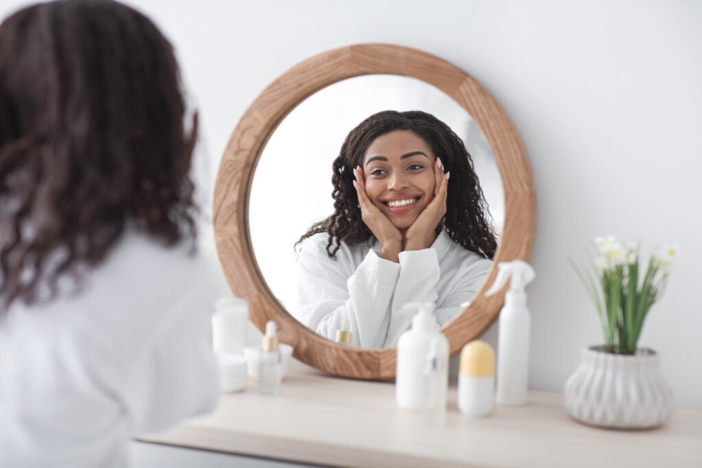 Woman admiring her skin at home after a minimalist skincare routine.