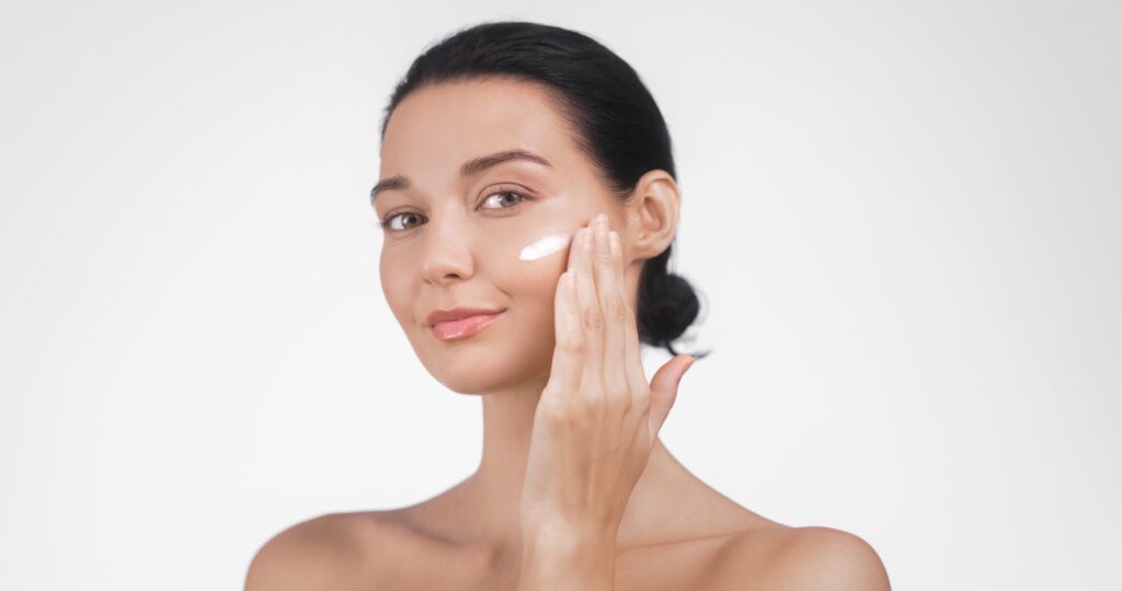 Client relaxing after a spa facial while applying gentle skincare in a bright, calming environment.