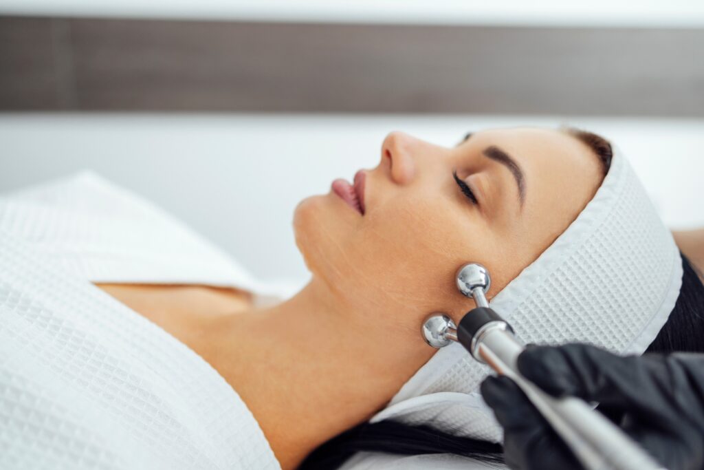 Esthetician performing a professional facial treatment focused on anti-aging and skin firming in a spa setting.