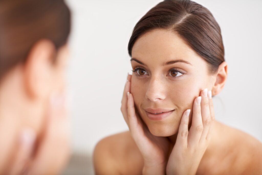 Woman admiring glowing face after receiving a professional facial treatment designed to hydrate her skin.
