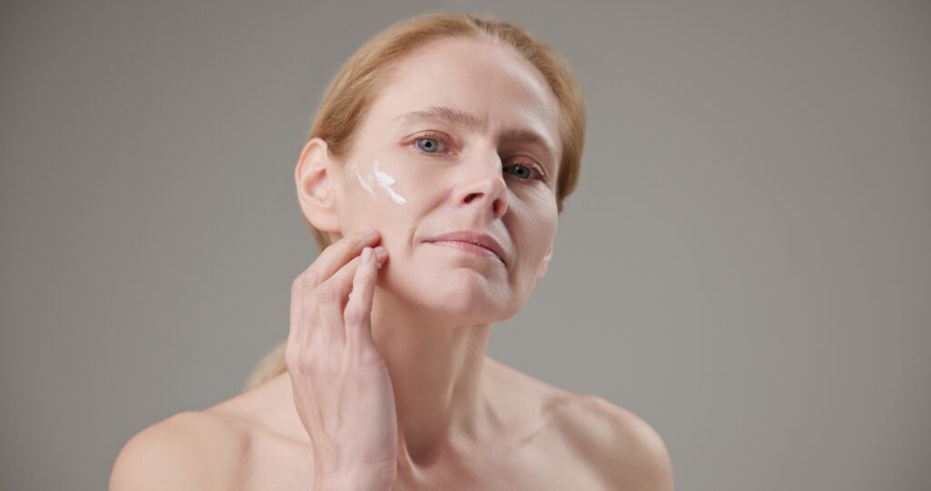 Woman applying gentle moisturizer to irritated skin while focusing on repairing a damaged skin barrier.
