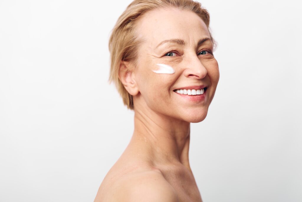 Woman smiling with lightweight sunscreen on her face in natural lighting.