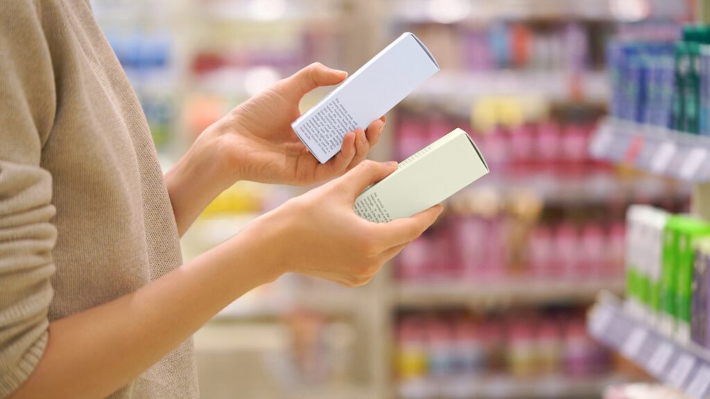 Customer holding a medical-grade skincare product in one hand and a drugstore skincare product in the other, comparing the two before choosing.