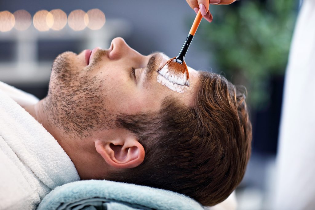 Male client receiving a customized professional facial from an esthetician in a relaxing spa setting.